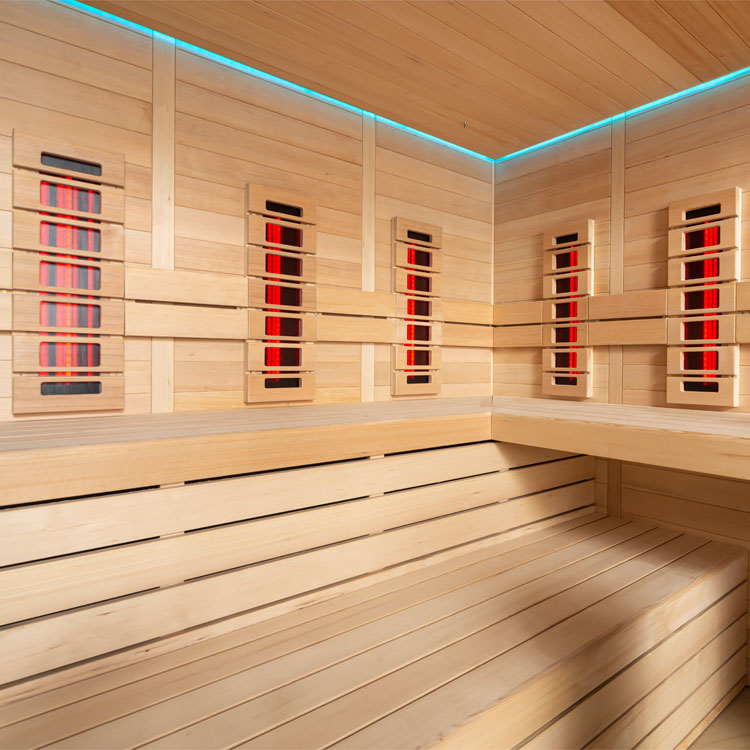 Holzsauna-Innenraum mit Infrarotstrahlern Bank, Eimer und Schöpfkelle; moderne Beleuchtung und Sanduhr an der Wand.